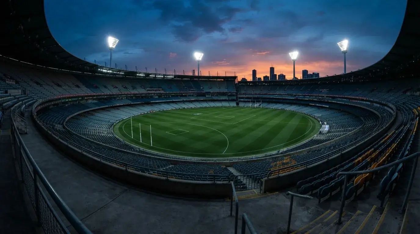 An empty football stadium with floodlight masts at dusk