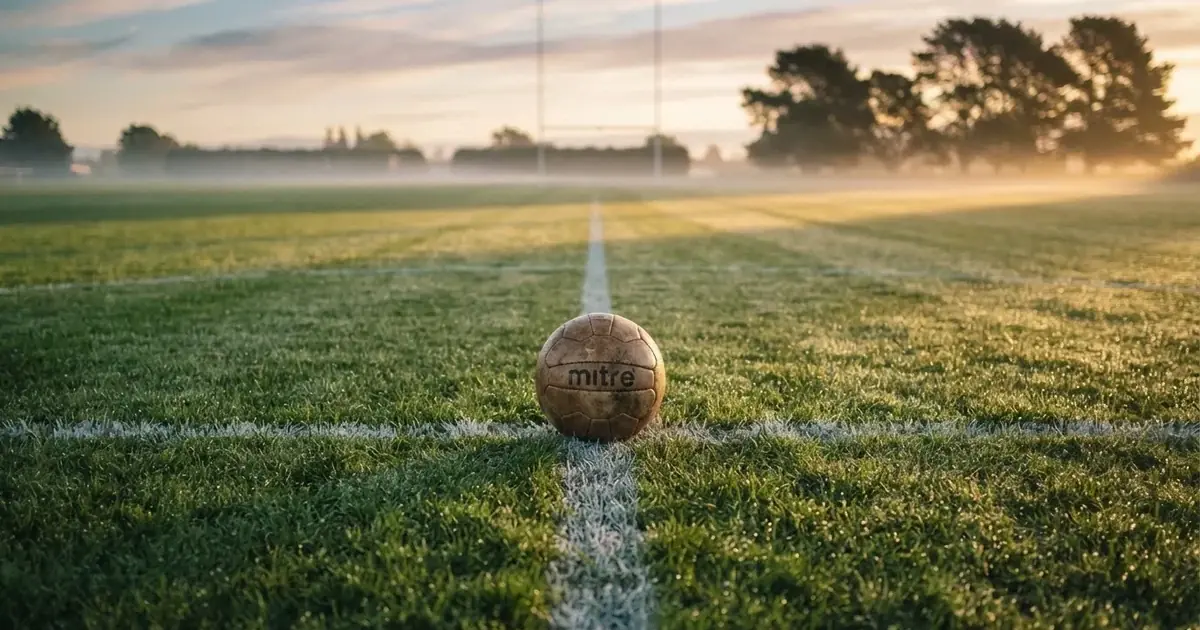 A ball on the centre spot of a grass pitch in morning light