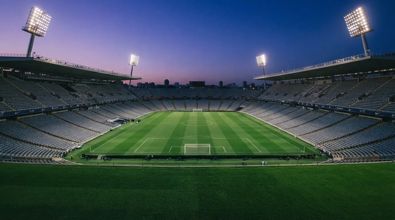 An empty football stadium with floodlight masts at dusk