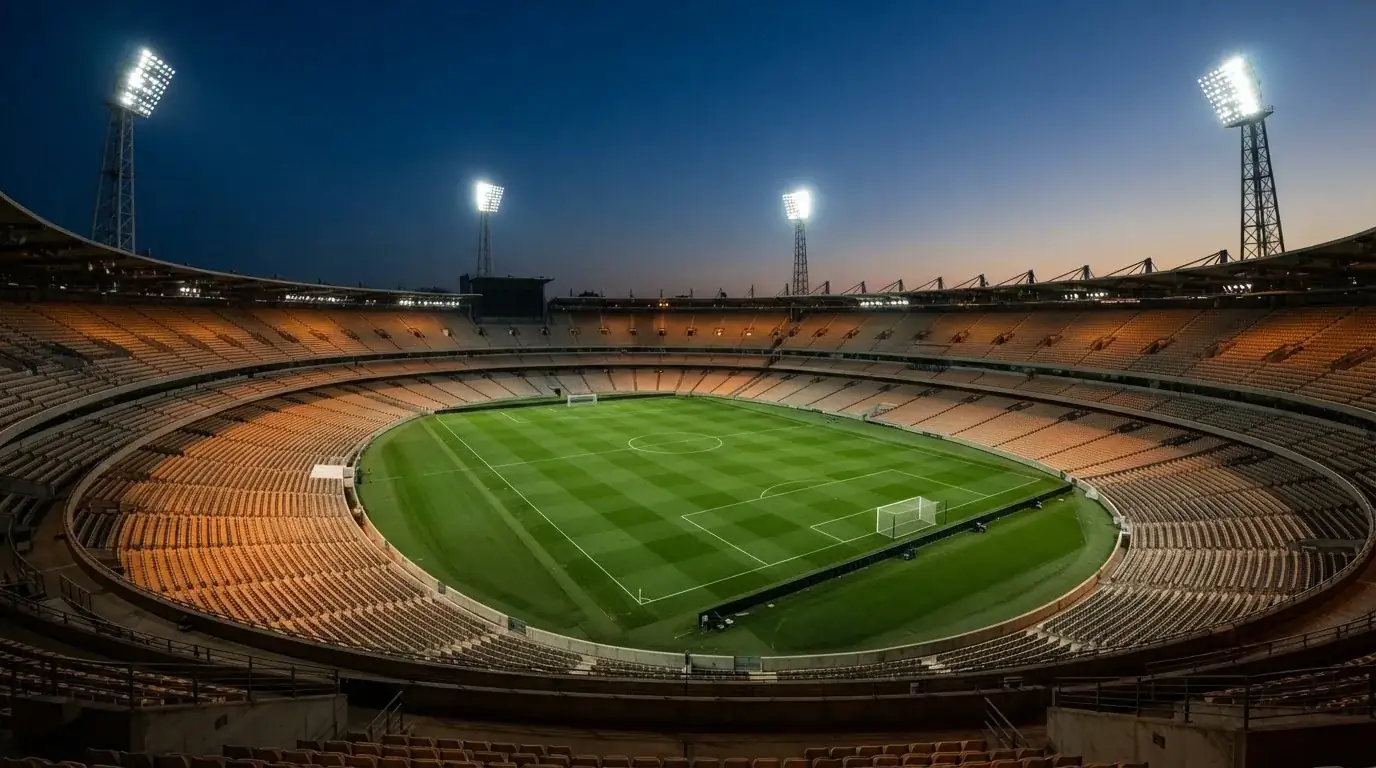 An empty football stadium with floodlight masts at dusk