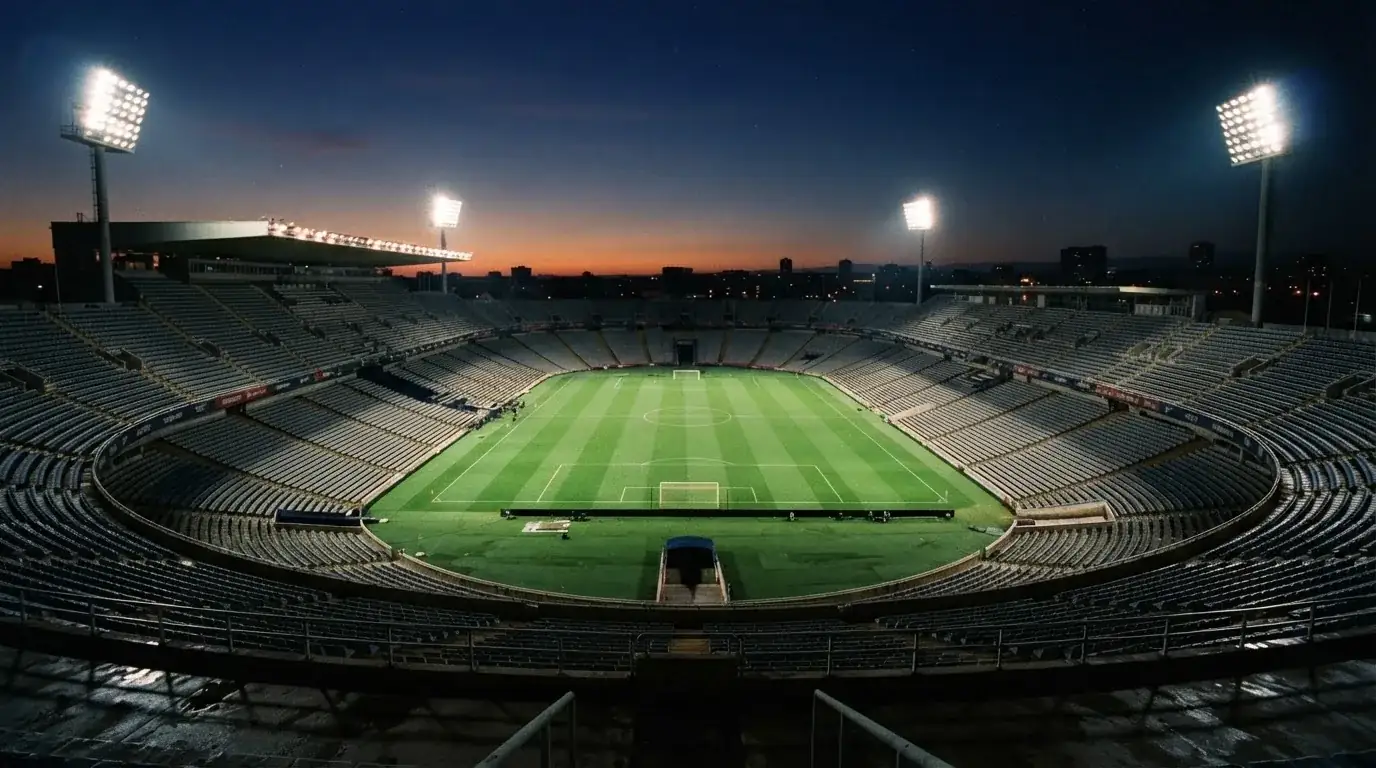 An empty football stadium with floodlight masts at dusk