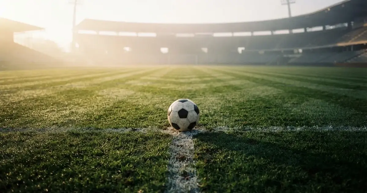 A ball on the centre spot of a grass pitch in morning light