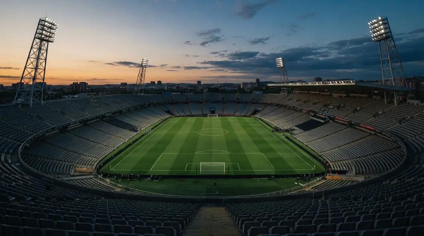 An empty football stadium with floodlight masts at dusk