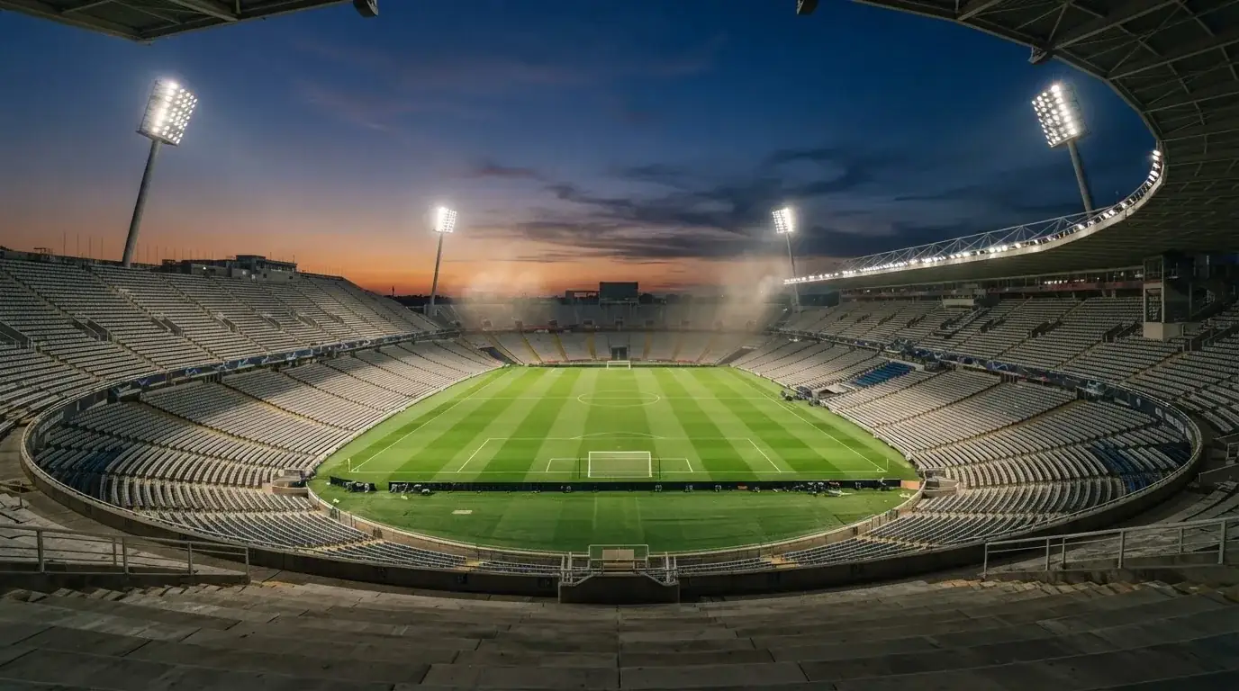 An empty football stadium with floodlight masts at dusk
