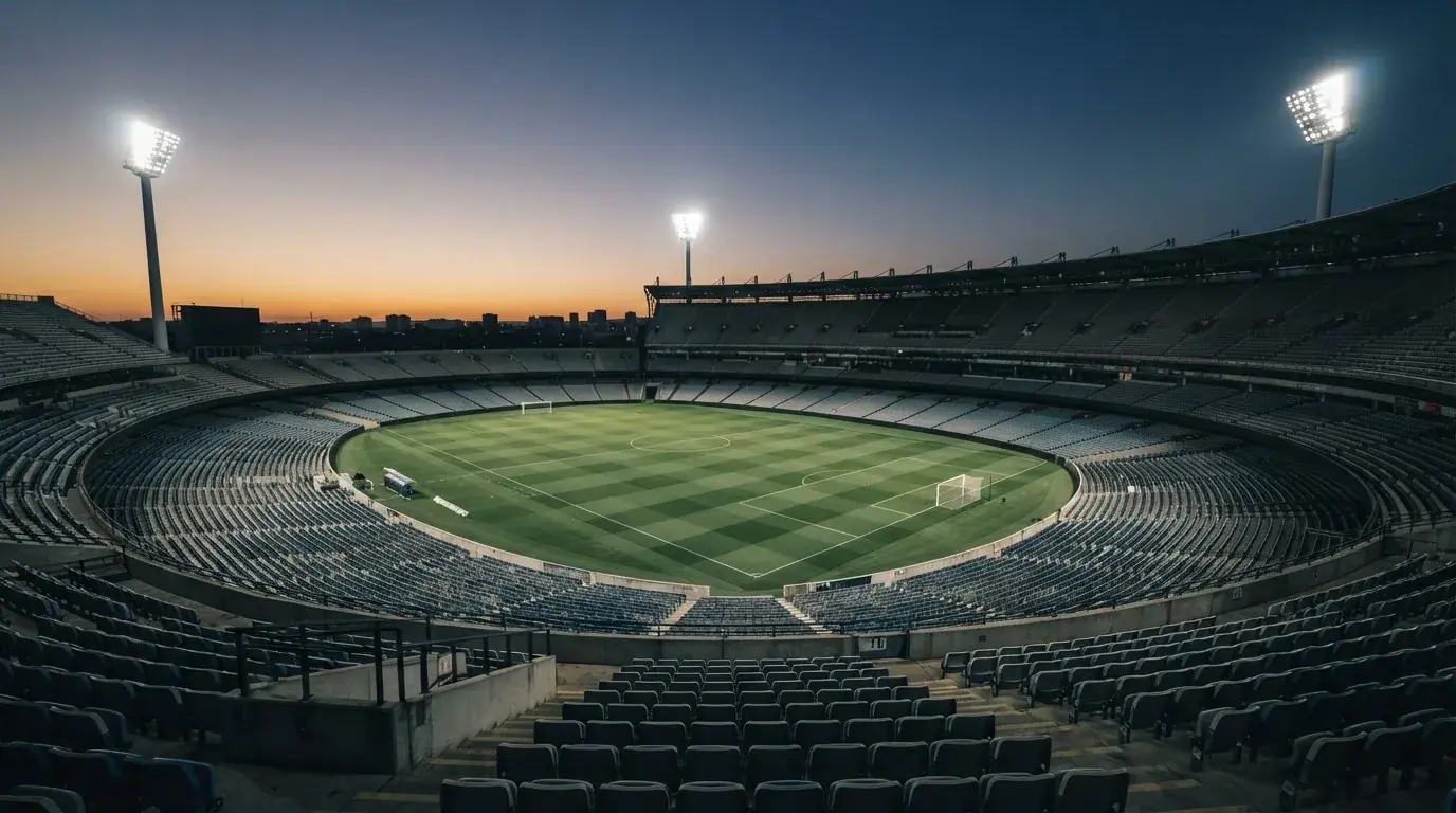 An empty football stadium with floodlight masts at dusk