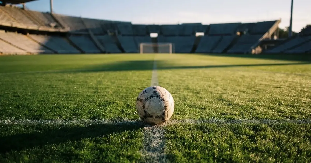 A ball on the centre spot of a grass pitch in morning light