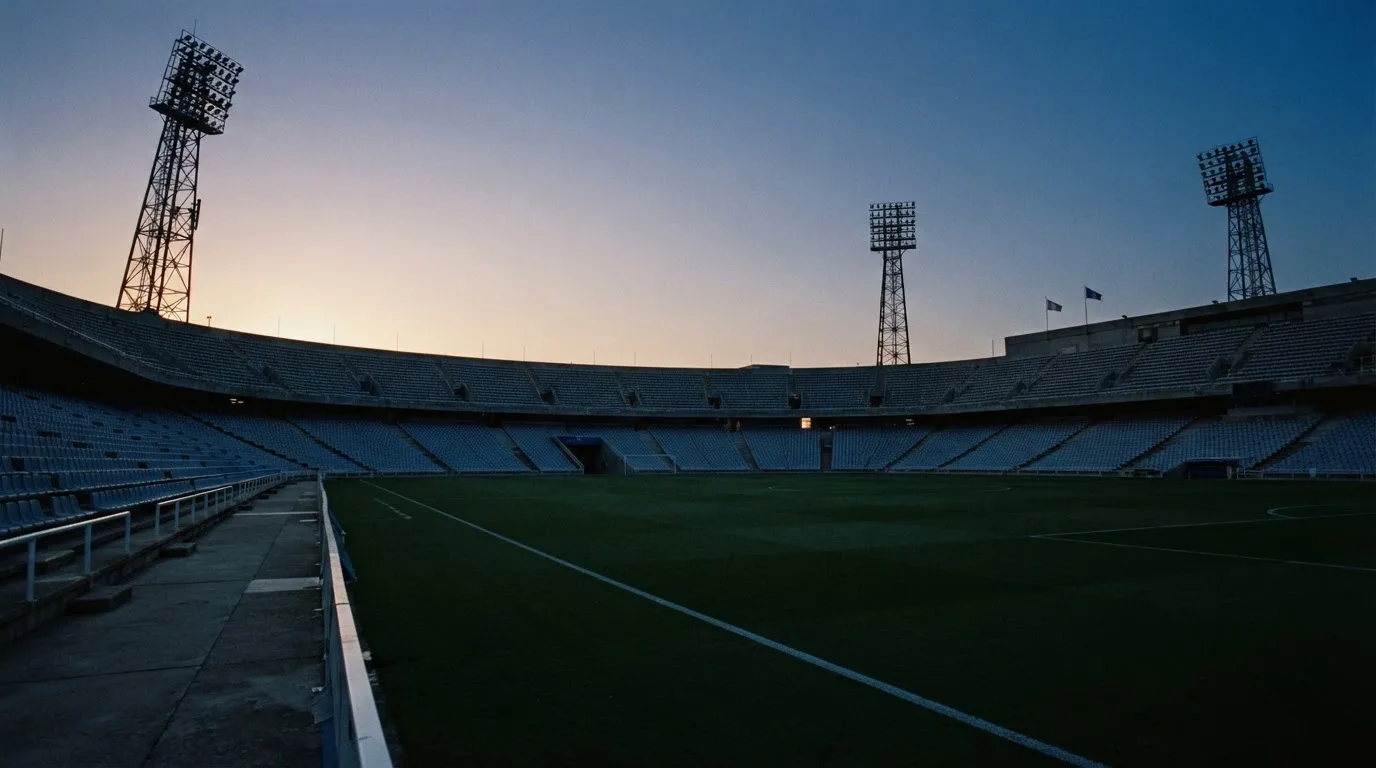 An empty football stadium with floodlight masts at dusk