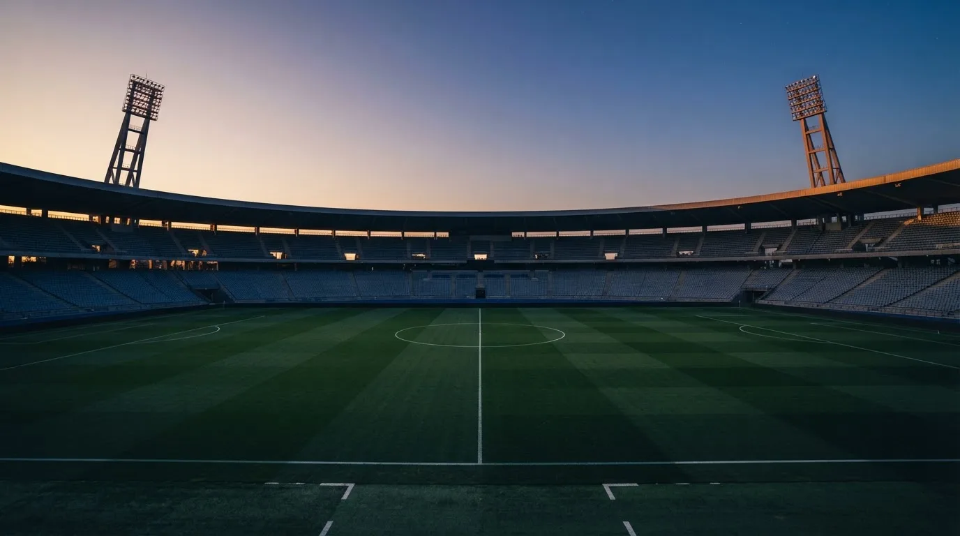An empty football stadium with floodlight masts at dusk