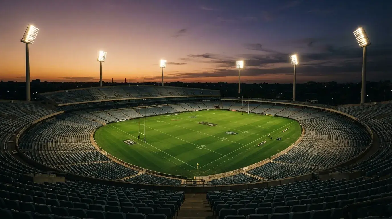 An empty football stadium with floodlight masts at dusk