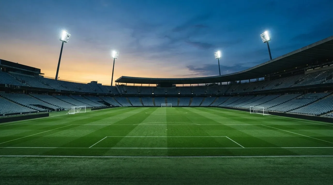 An empty football stadium with floodlight masts at dusk