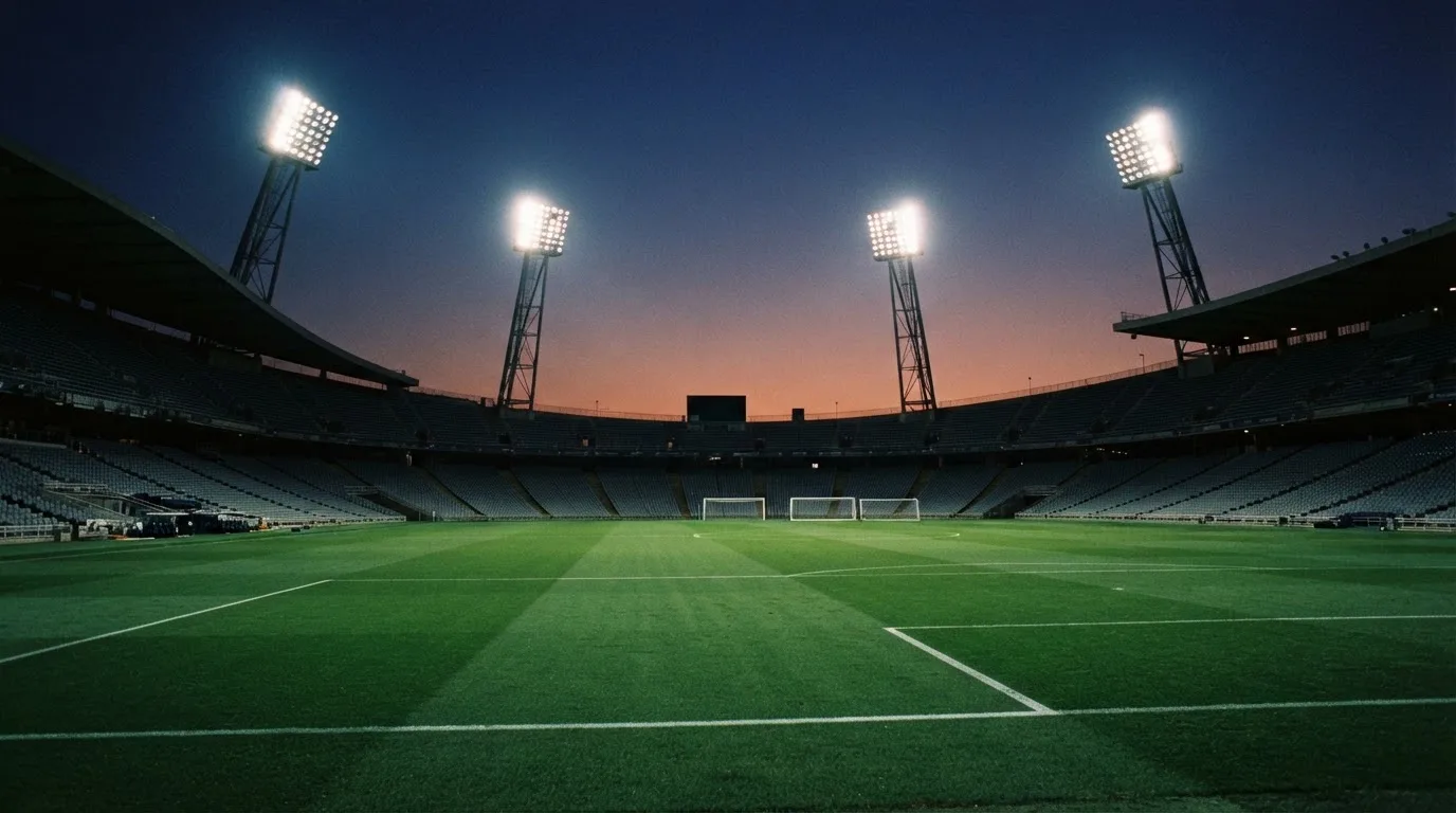 An empty football stadium with floodlight masts at dusk